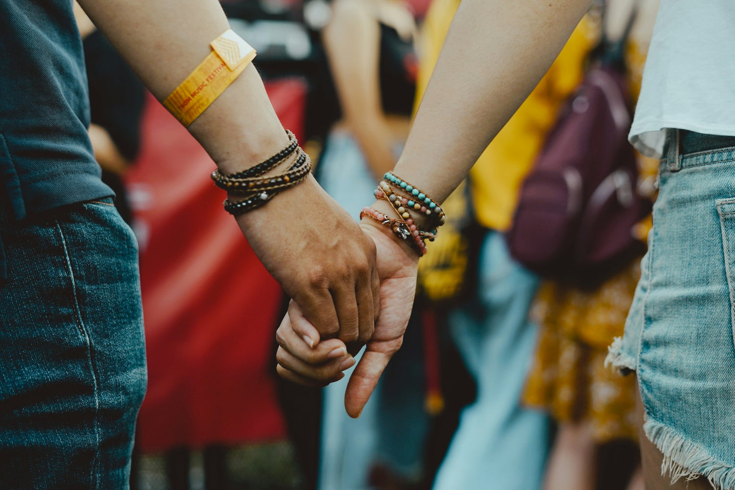 Zwei Menschen halten sich an den Händen, während sie mehrere Edelstein Armbänder tragen. Die Armbänder bestehen aus bunten Edelsteinperlen und wirken modern und stilvoll.