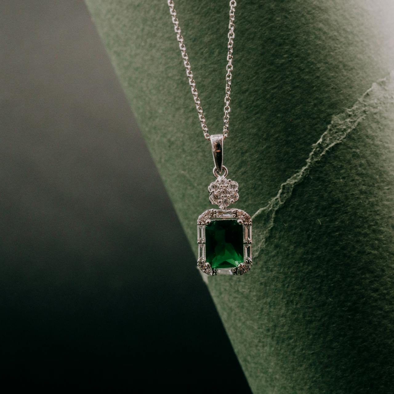 Ein edler Smaragd Schmuck-Anhänger mit rechteckigem Smaragd und funkelnden Akzenten hängt an einer feinen Silberkette.